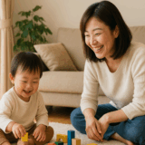 自然光の差し込むリビングで、幼い子どもが保護者のそばで安心して遊ぶ様子を写した、家庭の温かさが伝わる写真。