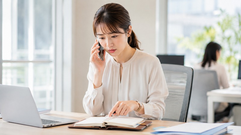 保育園からの連絡を受けて予定を確認する保護者
