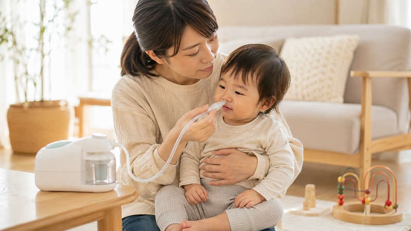 電動鼻水吸引器で子どものケアをする保護者