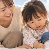 保育園へ行く朝に母親と一緒に身支度をする幼児
