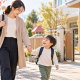 秋の朝に長袖を着て保育園へ登園する幼児と保護者