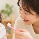 家庭で歯みがきを嫌がる幼児に優しく声をかける母親