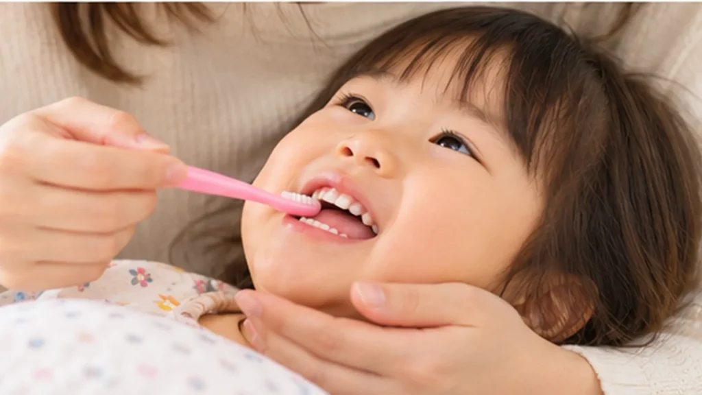 母親に優しく仕上げ磨きをしてもらう幼児