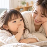 指しゃぶりをする幼児を優しく見守る母親
